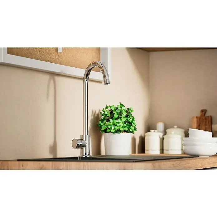 Grohe Spültischarmatur Blue Home Mono - Höhe: 37,9 cm, C-Auslauf, Chrom, Glänzend, Schwenkbar - Nahaufnahme einer eleganten Küchenarmatur aus Chrom vor einem modernen Spülbecken mit einer Zimmerpflanze und Küchenutensilien im Hintergrund.