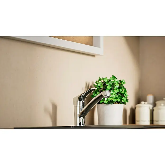 Hansgrohe Grifo de cocina Logis 120 - Cromo, Brillante - Primer plano de un grifo de cocina brillante junto a una maceta verde y recipientes blancos, transmitiendo una estética moderna.