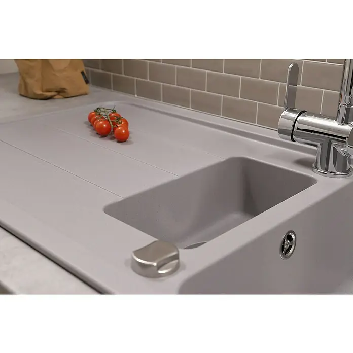 Respekta Einbauspüle Austin - 100 x 50 cm, Grau, Anzahl Becken: 1,5 Stk. - Nahaufnahme einer grauen Spüle mit frischen Tomaten und einem modernen Wasserhahn. Die Spüle integriert sich nahtlos in die Arbeitsplatte.