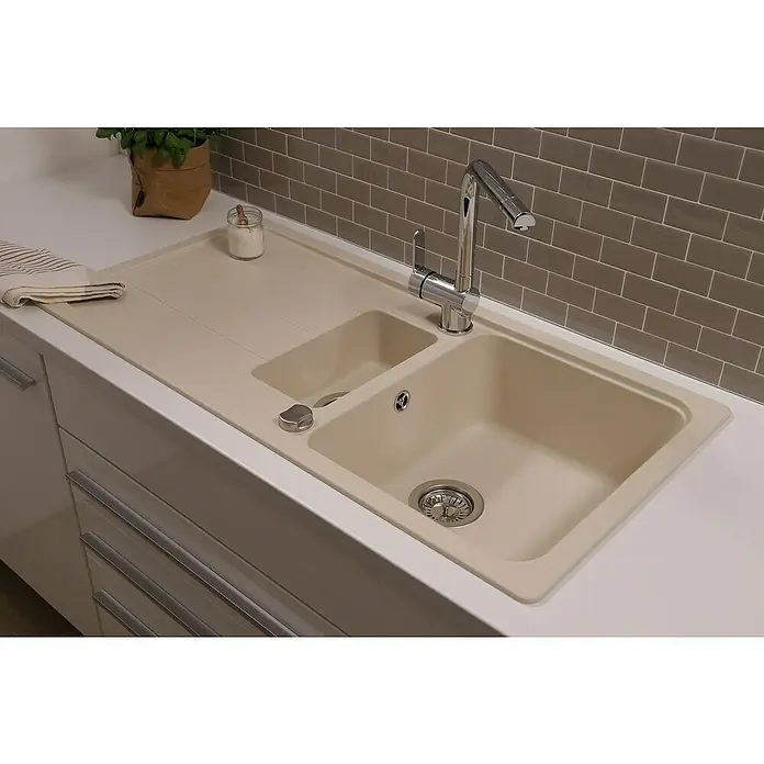 Respekta Einbauspüle Austin - 100 x 50 cm, Vanille, Anzahl Becken: 1,5 Stk. - Beige Küchenspüle mit Abtropffläche und modernem Chromhahn vor grauer Backsteinwand. Das Becken ist mit einem Edelstahl-Sieb ausgestattet.