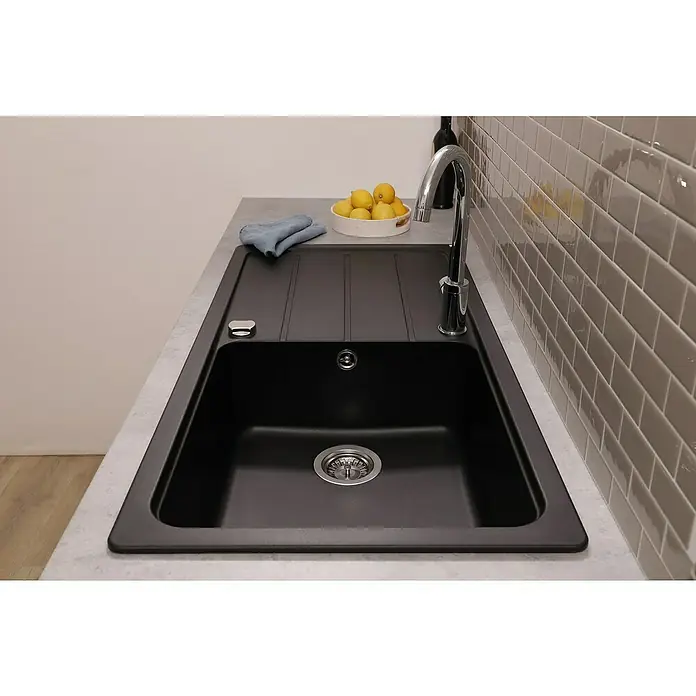 Respekta Einbauspüle Austin - 100 x 50 cm, Schwarz, Anzahl Becken: 1 Stk. - Schwarzes Spülbecken mit Abtropffläche, Armatur, Abfluss und Seifenspender auf einer grauen Arbeitsplatte. Zitronen in einer Schale und Handtuch daneben.