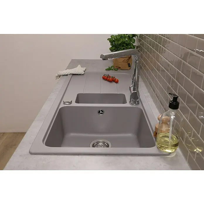 Respekta Einbauspüle Austin - 100 x 50 cm, Grau, Anzahl Becken: 1,5 Stk. - Nahaufnahme einer modernen grauen Spüle mit Abtropffläche, Armatur und einigen dekorativen Elementen auf einer Küchentheke.
