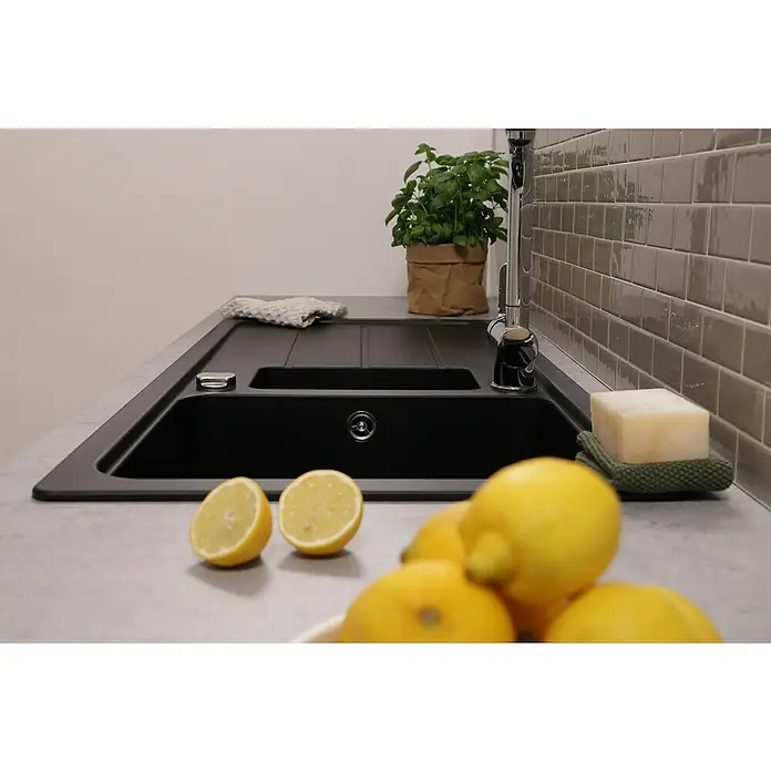 Respekta Einbauspüle Austin - 100 x 50 cm, Schwarz, Anzahl Becken: 1,5 Stk. - Moderne Küchenspüle aus schwarzem Granit mit Abtropffläche, umgeben von Zitronen, Seife und einem Basilikumtopf, ideal für eine stilvolle Küchengestaltung.