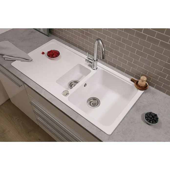 Respekta Einbauspüle Austin - 100 x 50 cm, Weiß, Anzahl Becken: 1,5 Stk. - Detailaufnahme einer modernen weißen Küchenspüle mit Abtropffläche, Armatur und frischen Früchten.