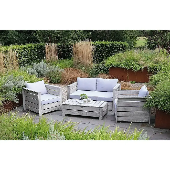 Joda Loungemöbel-Set Brisbane - 5 -tlg., Eukalyptus, Hellgrau - Einladende Gartenmöbel-Garnitur mit Couch, Sessel und Tisch aus hellem Holz inmitten üppiger Vegetation.