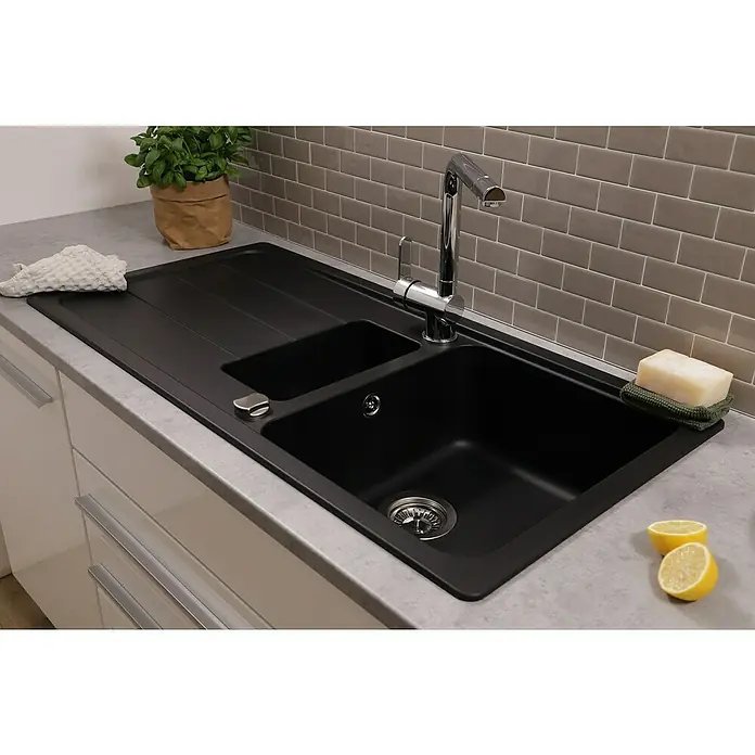Respekta Einbauspüle Austin - 100 x 50 cm, Schwarz, Anzahl Becken: 1,5 Stk. - Detailaufnahme eines schwarzen Spülbeckens mit Abtropffläche, Armatur, Seife, Lappen und Zitronen in einer modernen Küche.