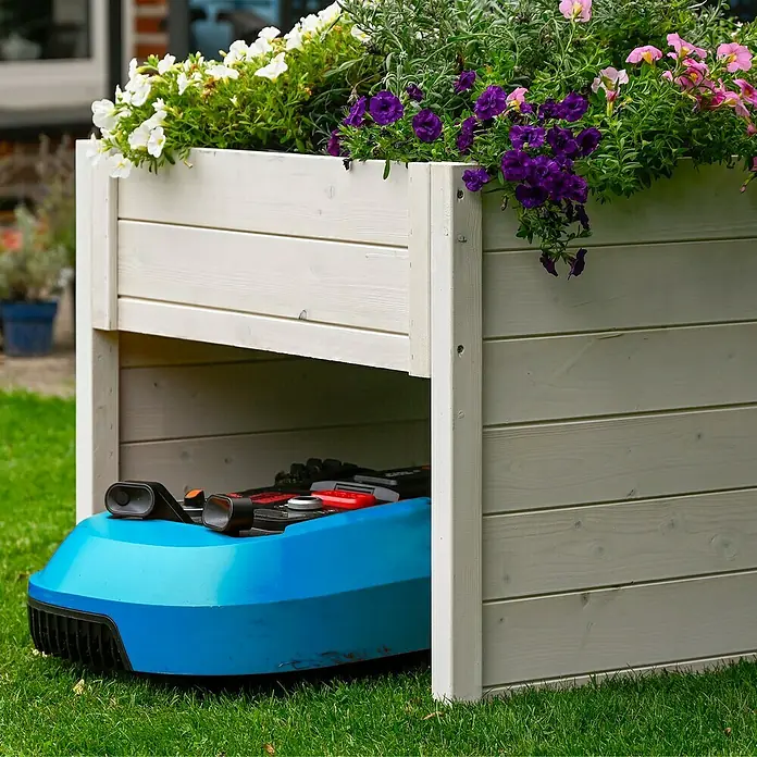 Dobar Mähroboter-Garage - L x B x H: 73 x 79 x 56 cm, Weiß - Das Bild zeigt einen blauen Mähroboter, der unter einem weißen Holzpflanzkasten mit bunten Blumen geparkt ist.