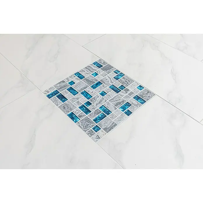 Mosaikfliese Crystal Mix XCM MC589 - 30 x 30 cm, Grau, Glänzend - Nahaufnahme eines quadratischen Mosaikfliesen-Einsatzes mit grauen und blauen Akzenten auf weißen Marmorfliesen.