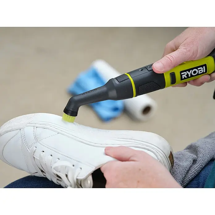 Ryobi 4V USB Akku-Reinigungsbürste RDS4-0 - 4 V, Ohne Akku - Detailaufnahme einer Person, die mit einem Ryobi-Reinigungsgerät einen weißen Sneaker säubert, um seine Sauberkeit wiederherzustellen.