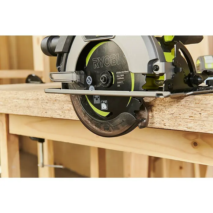 Ryobi ONE+HP Akku-Handkreissäge RC S18X1-0 - Ohne Akku, Durchmesser Sägeblatt: 184 mm, 4.500 U/min - Nahaufnahme einer Ryobi Kreissäge, die auf einer Holzoberfläche steht, wobei die Details des Sägeblatts und der Konstruktion hervorgehoben werden.