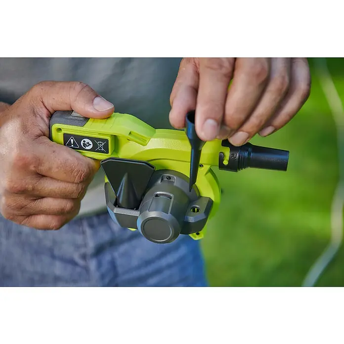 Ryobi 4V USB Akku-Gebläse RVI4-0 - 4 V, Ohne Akku, Luftmenge: 200 l/min - Nahaufnahme eines gelben Laubbläsers beim Anbringen eines schwarzen Düsenaufsatzes vor einem unscharfen grünen Hintergrund.