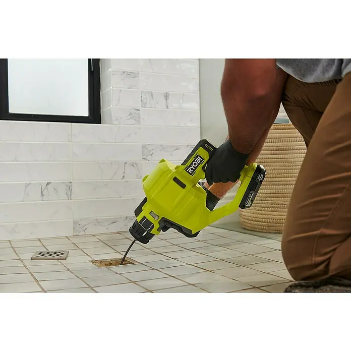 Ryobi ONE+ Akku-Rohrreinigungsgerät RDA18-0 - Ohne Akku - Eine gelbe Ryobi-Abflussreinigungsmaschine wird zum Reinigen eines verstopften Abflusses in einer gefliesten Dusche verwendet.