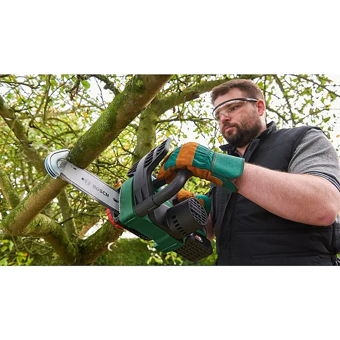 Bosch Professional AMPShare 18V Sägekette - Passend für: Bosch Professional AMPShare 18V Akku-Astsäge GKE 18V-20 - Ein Mann, der mit einer Bosch Akku-Kettensäge einen Ast sägt. Die Kettensäge ist grün und schwarz. Schutzbrille und Handschuhe werden getragen.