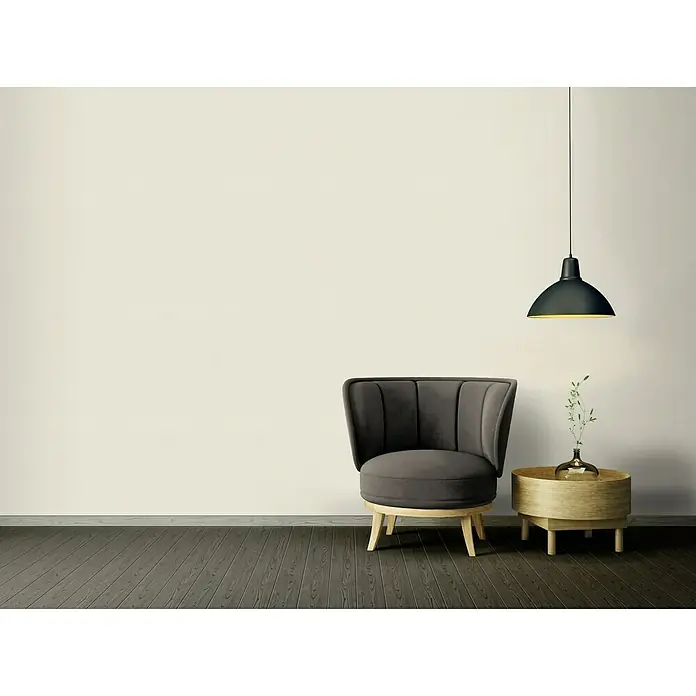 A.S. Création Ethnic Origin Vliestapete I - Creme, Uni, 10,05 x 0,53 m - Einrichtung mit einem eleganten grauen Sessel auf einem Holzsockel und einem Beistelltisch mit einer dekorativen Vase unter einer schwarzen Lampe.