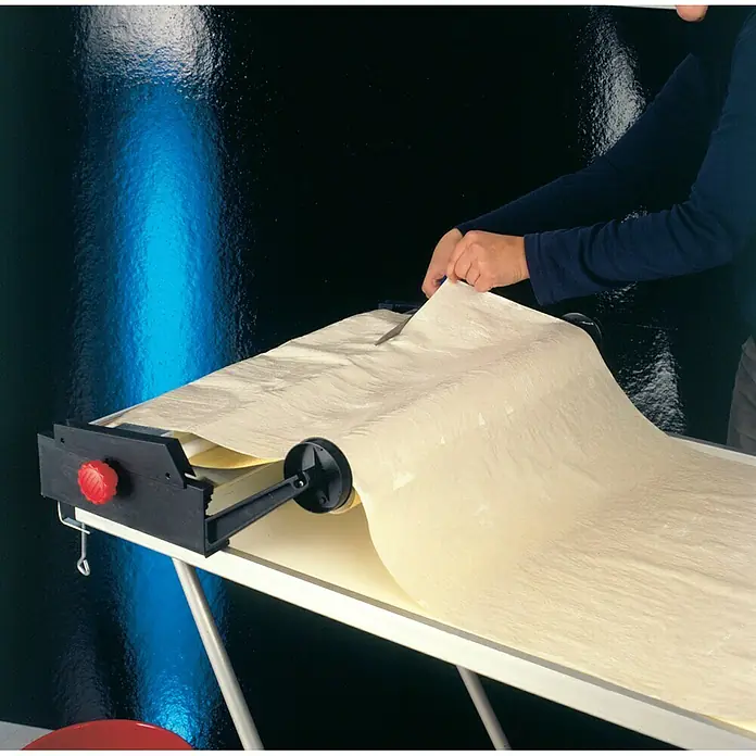 Decora Tapetenkleistergerät - Geeignet für: Euro Rollen 53 cm - Nahaufnahme eines Papierrollenschneiders mit einer Rolle Pergamentpapier, der auf einem Tisch steht.