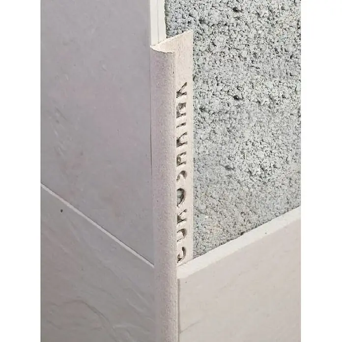 Perfil para baldosas PVC Crema rústica - 2,5 m x 12 mm - Detalle de un borde de azulejo blanco con esquina redondeada y diseño perforado, que ofrece un acabado limpio y seguro.
