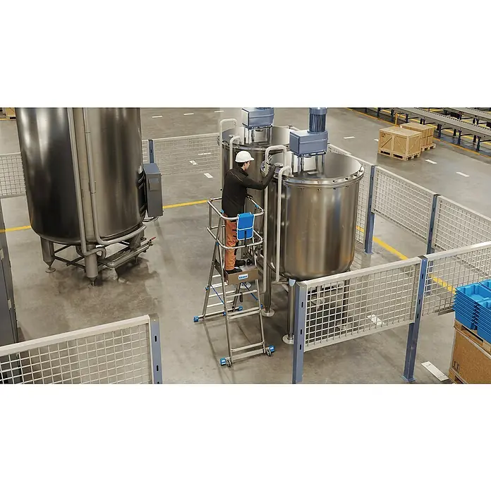 Krause Sprossen-Gelenk-Teleskopleiter Skymatic 3-5 Sprossen - Arbeitshöhe: 3,3 m, Anzahl Tritte: 5 Stk., Aluminium - Ein Mann auf einer mobilen Arbeitsbühne von Krause, die vor großen Edelstahltanks in einer Produktionshalle steht.