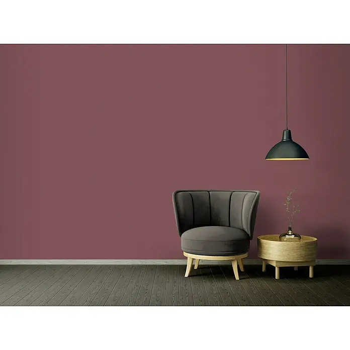 A.S. Création Ethnic Origin Vliestapete - Violett, Uni, 10,05 x 0,53 m - Elegantes Interieur mit einem grauen Samtsessel, einem hellen Holztisch und einer modernen schwarzen Hängelampe vor einer bordeauxroten Wand.
