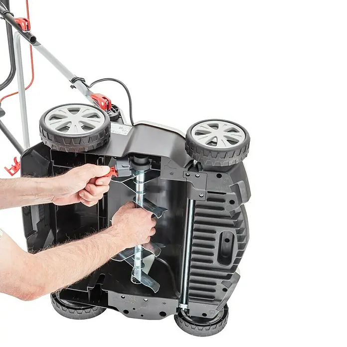 AL-KO Elektro-Vertikutierer-Lüfter Combi Care 36 E Comfort - 1.500 W, Arbeitsbreite: 36 cm - Ein Mann justiert die Klingen eines AL-KO Vertikutierers, der auf dem Rücken liegt. Das Gerät ist mit Rädern ausgestattet.