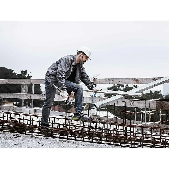 Bellota Martillo de albañil 8030-T BI - Largo: 500 mm, 600 g, Acero - Un trabajador de la construcción con casco y guantes trabaja la armadura al aire libre con un martillo y madera.