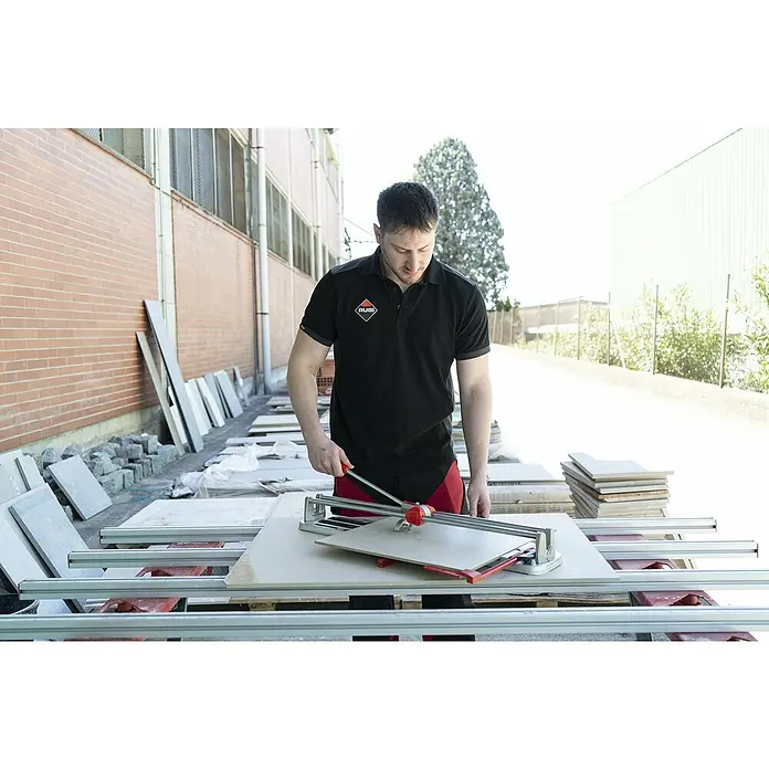 Rubi Cortador manual de azulejos Star Platinum - Longitud de corte máx.: 630 mm, Espesor máx. de azulejo: 12 mm - Un hombre corta azulejos con un cortador de azulejos Rubi, asegurando cortes precisos para proyectos de construcción.