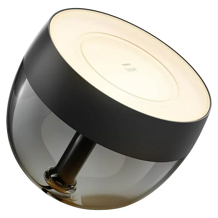 Philips Hue LED-Tischleuchte Iris - Schwarz/Transparent, Höhe: 19,4 cm - Nahaufnahme einer Philips Hue Tischleuchte mit einem runden, leuchtenden Lampenschirm und einem transparenten, getönten Glaskörper.