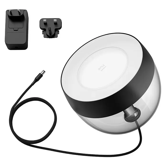 Philips Hue LED-Tischleuchte Iris - Schwarz/Transparent, Höhe: 19,4 cm - Nahaufnahme einer Philips Hue Lampe mit Netzteilen und Kabel, die ihr modernes Design und ihre Funktionalität hervorhebt.