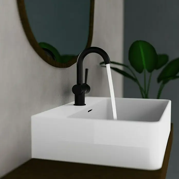 Camargue Waschtischarmatur Merida - Schwarz, Matt - Moderne Waschbeckenarmatur in Schwarz mit fließendem Wasser in einem stilvollen Badezimmer mit Spiegel und Pflanze im Hintergrund.