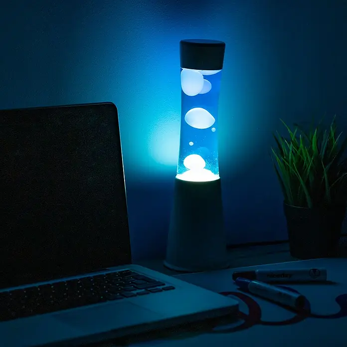 Lámpara de sobremesa decorativa lava mini - 25 W, L x An x Al: 9 x 9 x 30 cm, Blanco, Azul - Lámpara de lava azul sobre un escritorio junto a un ordenador portátil y material de oficina, creando un ambiente relajante.