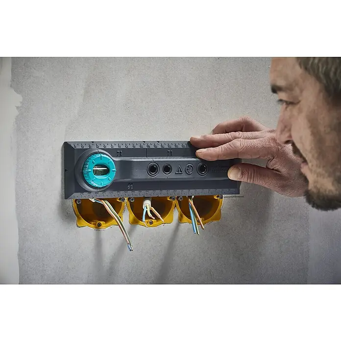 Wolfcraft Plantilla de perforación - Específico para: Instalación de cajetines eléctricos en ladrillo - Artesano utilizando un nivel en cajas eléctricas amarillas conectadas a una pared.