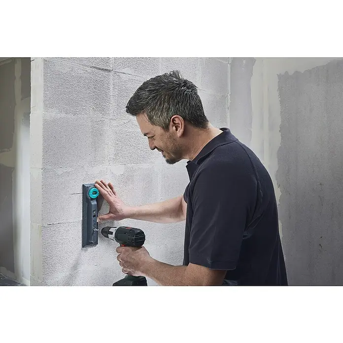 Wolfcraft Plantilla de perforación - Específico para: Instalación de cajetines eléctricos en ladrillo - Un hombre monta algo en una pared con un juego de tacos de Wolfcraft. El juego garantiza orificios precisos y una sujeción segura.