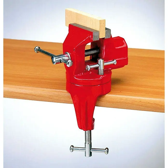 Mordaza giratoria para tornillo de banco 105210 - L x An x Al: 7 x 17 x 23 cm, Anchura de sujeción: 60 mm, Acero - Tornillo de banco rojo con pieza de madera sujetada sobre una mesa. Ideal para trabajos de taller y proyectos de afición.