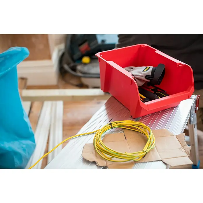 Stanley Gaveta - Tamaño: 4, Rojo - Primer plano de una caja de herramientas roja con materiales de trabajo como cable y guantes sobre un banco de trabajo.