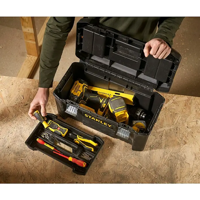 Stanley Caja para herramientas Mega Cantilever - 19'', 48,2 x 25,4 x 25 cm - Caja de herramientas negra Stanley con herramientas amarillas, parcialmente abierta, con bandeja de herramientas sobre superficie de madera.