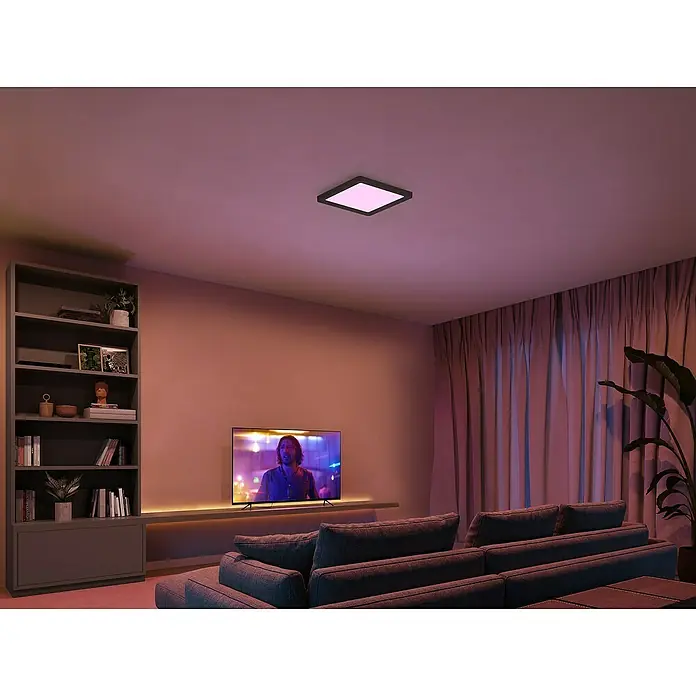 Philips Hue LED-Panel White & Color Ambiance Tento S - 10,6 W, L x B x H: 29,5 x 29,5 x 3,5 cm, Schwarz, RGBW - Modernes Wohnzimmer mit einem quadratischen Deckenlicht, das sanftes, farbiges Licht spendet und eine warme Atmosphäre erzeugt.