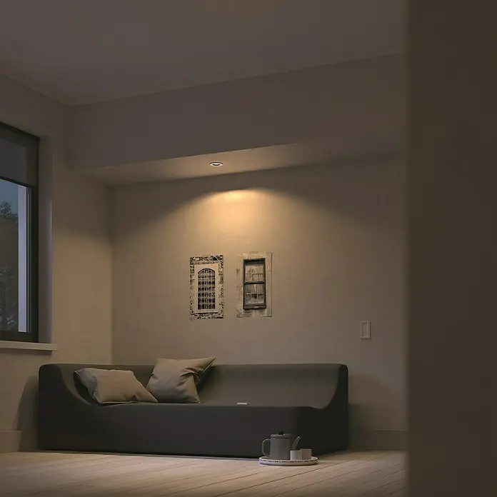 Philips Hue LED-Einbauspot White Ambience Recessed Milliskin - 4,2 W, Ø x H: 9 x 10 cm, Alu, 1 Stk., Kaltweiß - Ein Wohnzimmer mit einem grauen Sofa, zwei Kissen, zwei Fensterbildern und einer Teekanne. Das Zimmer wird von einer Deckenleuchte beleuchtet.