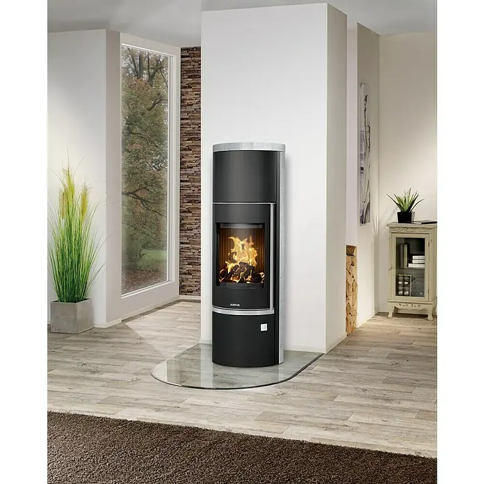 Justus Kaminofen Faro Aqua 2.0 - 8,5 kW, Raumheizvermögen: 200 m³, Material Verkleidung: Speckstein, Schwarz/Speckstein - Elegantes Interieur mit einem modernen schwarzen Kaminofen auf einer Glasplatte, der Wärme und Stil in den Raum bringt.
