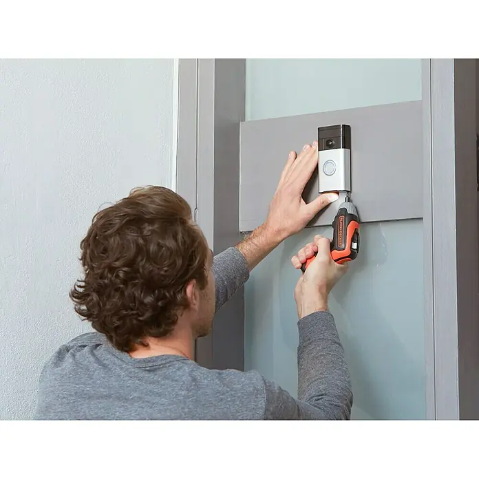 Black+Decker Atornillador de batería BCF611CK-QW - 3,6 V, 1 batería - Un hombre instala un timbre Ring con un destornillador inalámbrico Black+Decker en una pared gris.