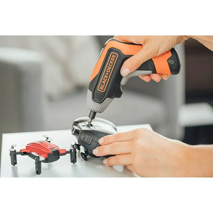Black+Decker Atornillador de batería BCF611CK-QW - 3,6 V, 1 batería - Se utiliza un destornillador inalámbrico Black+Decker para reparar un pequeño dron sobre una mesa.
