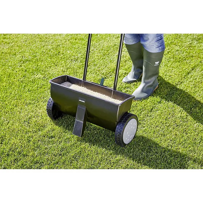 Gardol Carro esparcidor ST 451 - 12 l, Plástico - Imagen de un esparcidor de semillas sobre el césped. La herramienta de jardín está llena de fertilizante lista para usar.