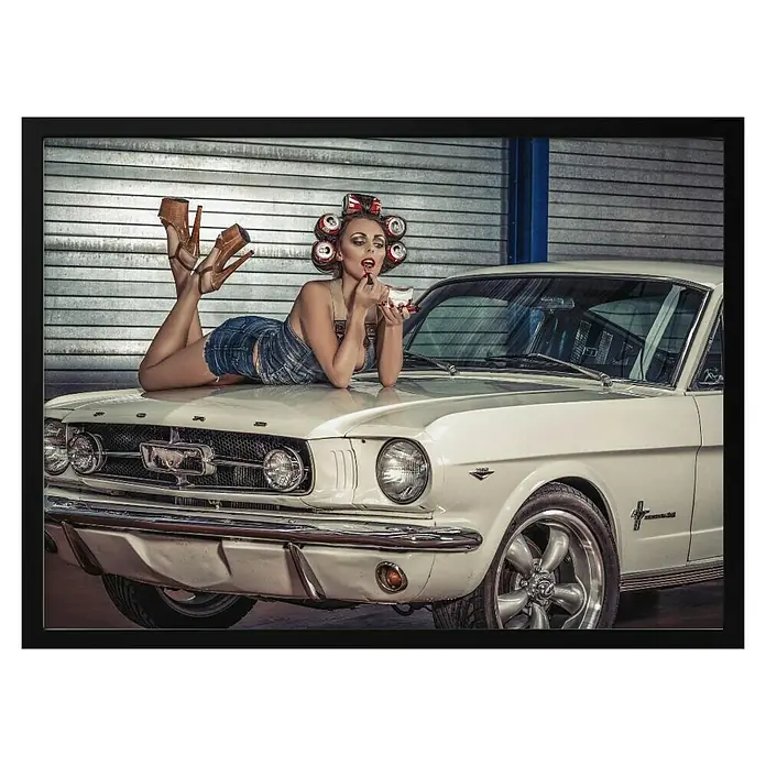 Papermoon Bild - Drive my Car, B x H: 140 x 100 cm, Ohne Passepartout, Rahmen Schwarz - Eine atemberaubende Aufnahme eines Oldtimer-Ford Mustang in Weiß, mit einer Frau im Pin-up-Stil auf der Motorhaube.