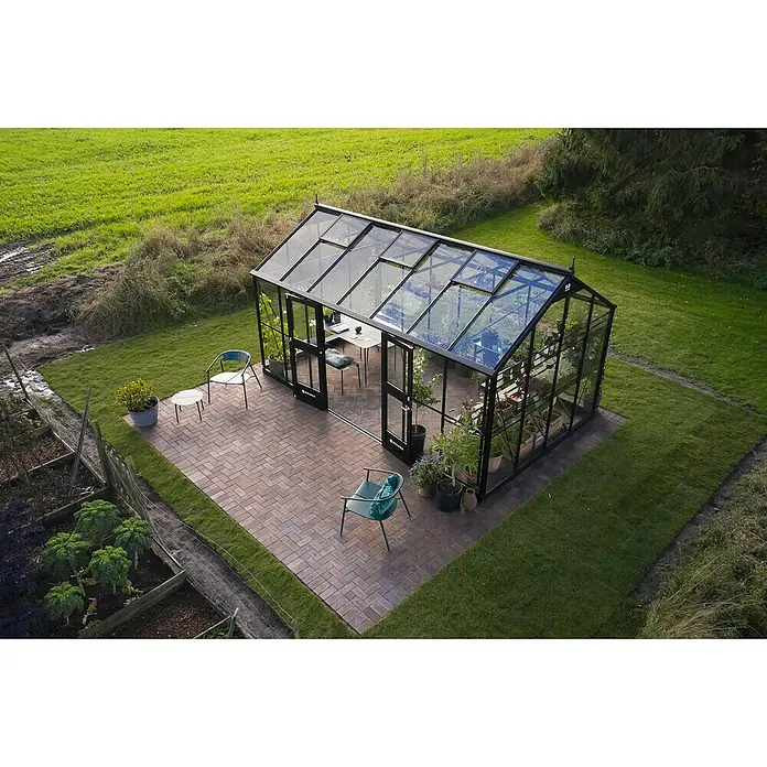 Juliana Gewächshaus Jubii 60 - Material Seitenwand: Glas, 3 mm, Schwarz - Elegantes Gewächshaus mit schwarzem Rahmen, eingebettet in eine grüne Gartenlandschaft, perfekt für Pflanzenzucht und Entspannung.