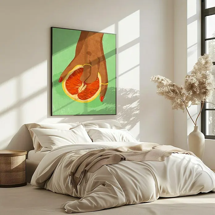 Papermoon Bild - Fruitlover, B x H: 40 x 50 cm, Ohne Passepartout, Rahmen Eiche - Ein gerahmtes Kunstwerk mit einer Hand, die eine halbe Grapefruit hält, hängt über einem Bett mit weißer Bettwäsche und einem beigen Überwurf.