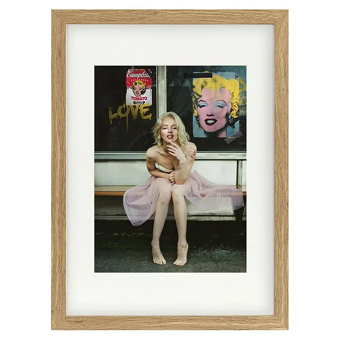 Papermoon Bild - New Marilyn, B x H: 40 x 50 cm, Mit Passepartout, Rahmen Eiche - Gerahmtes Foto mit einer blonden Frau im Tutu vor Marilyn Monroe-Graffiti, das eine künstlerische Atmosphäre erzeugt.