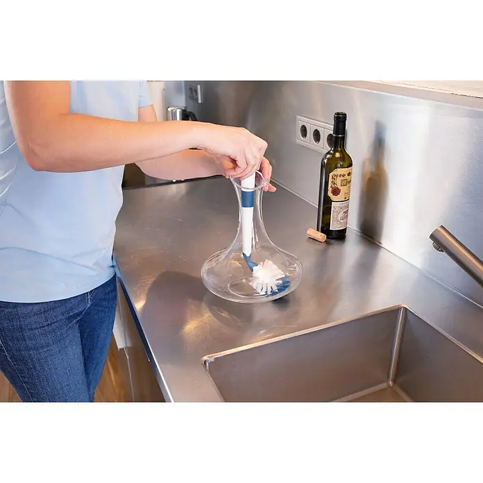 Unger Spülbürste Flex - 32 cm, Kunststoff/Gummi - Eine Person reinigt eine Weindekantierflasche mit einer Reinigungsbürste in einer Küche mit Edelstahlspüle und Arbeitsplatte.