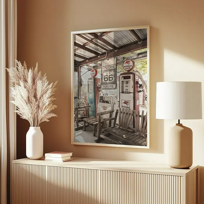 Papermoon Bild - Route 66 Gas Station, B x H: 70 x 100 cm, Ohne Passepartout, Rahmen Eiche - Ein gerahmtes Bild von einer Route 66 Tankstelle hängt an einer Wand über einem Sideboard mit Lampe und Vase.