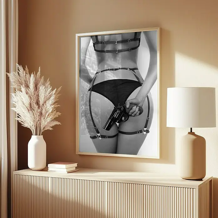 Papermoon Bild - Love & a loaded Gun, B x H: 40 x 50 cm, Ohne Passepartout, Rahmen Eiche - Ein gerahmtes, schwarz-weißes Kunstwerk mit einer Frau in Dessous, die eine Waffe hält, hängt über einer modernen Kommode.