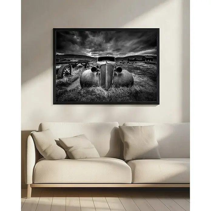 Papermoon Bild - Too Old to Drive, B x H: 110 x 80 cm, Mit Passepartout, Rahmen Schwarz - Schwarz-Weiß-Foto eines Oldtimers in einem dunklen Rahmen, der über einem cremefarbenen Sofa an einer hellen Wand hängt.