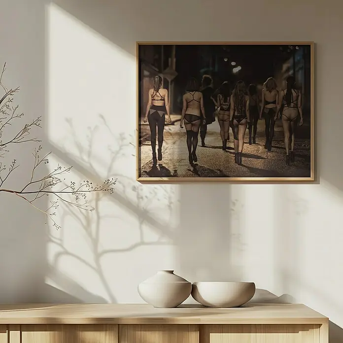 Papermoon Bild - Street Women, B x H: 110 x 80 cm, Mit Passepartout, Rahmen Eiche - Gerahmtes Bild mit einer Gruppe von Frauen in Dessous, die eine Gasse entlanggehen, hängt über einem Sideboard mit zwei Keramikvasen.