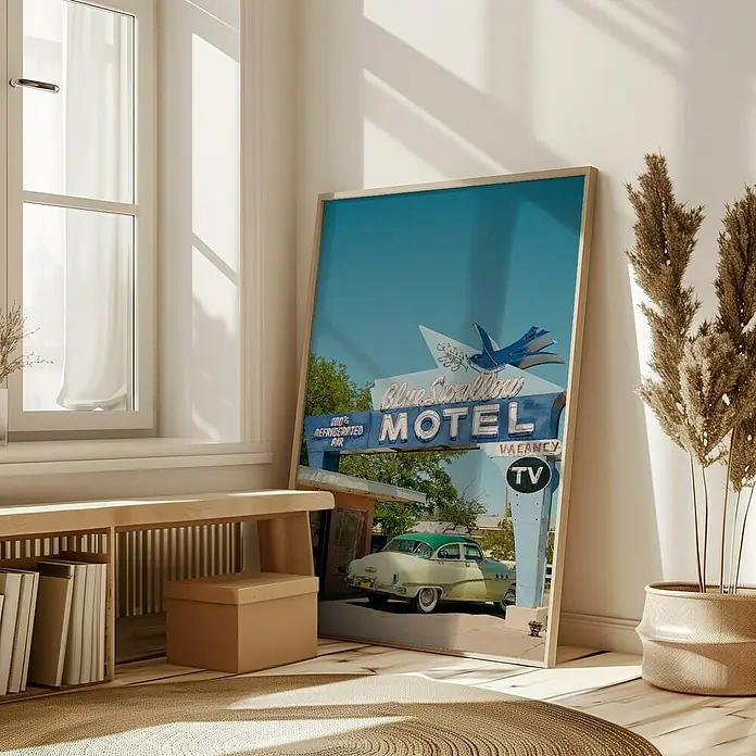 Papermoon Bild - Route 66, B x H: 40 x 50 cm, Mit Passepartout, Rahmen Eiche - Ein gerahmtes Poster des Blue Swallow Motels, das an eine Wand gelehnt ist und eine Vintage-Atmosphäre in einem hellen, modernen Raum schafft.